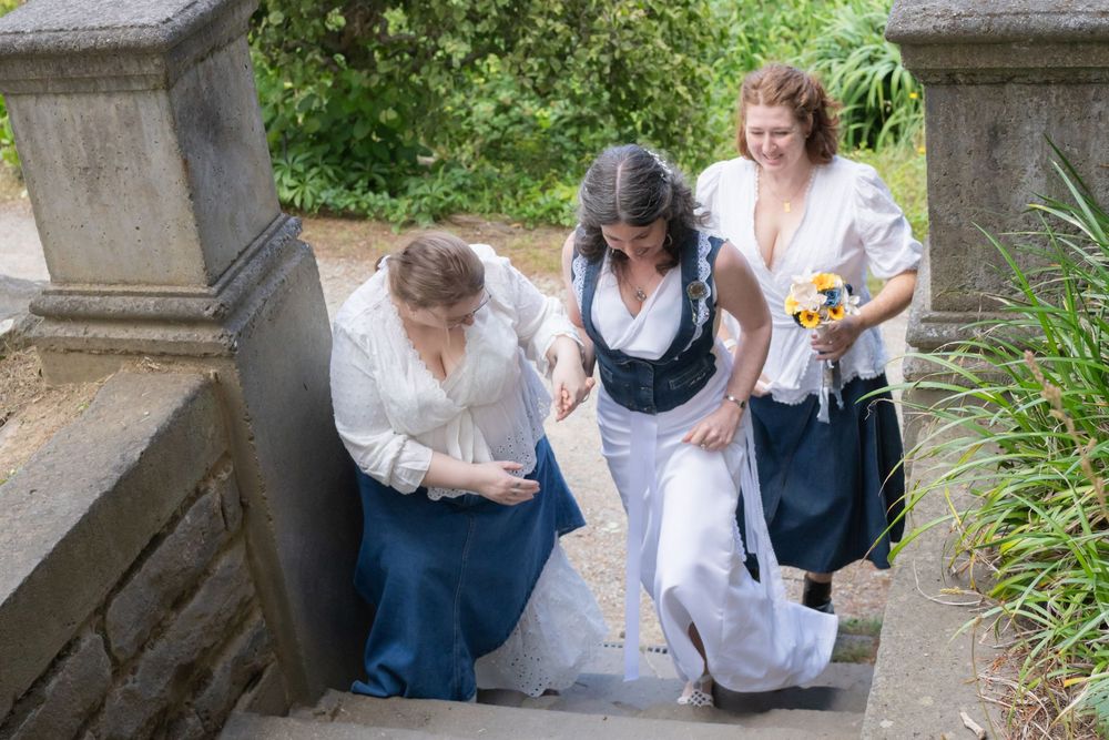 Group of people sitting on stone steps in a garden setting during a casual outdoor gathering.