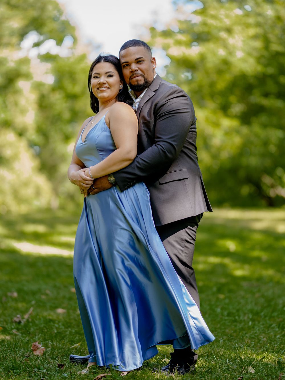 A romantic couple embraces while wearing formal attire in a sunlit outdoor garden setting beautiful engagement shoot