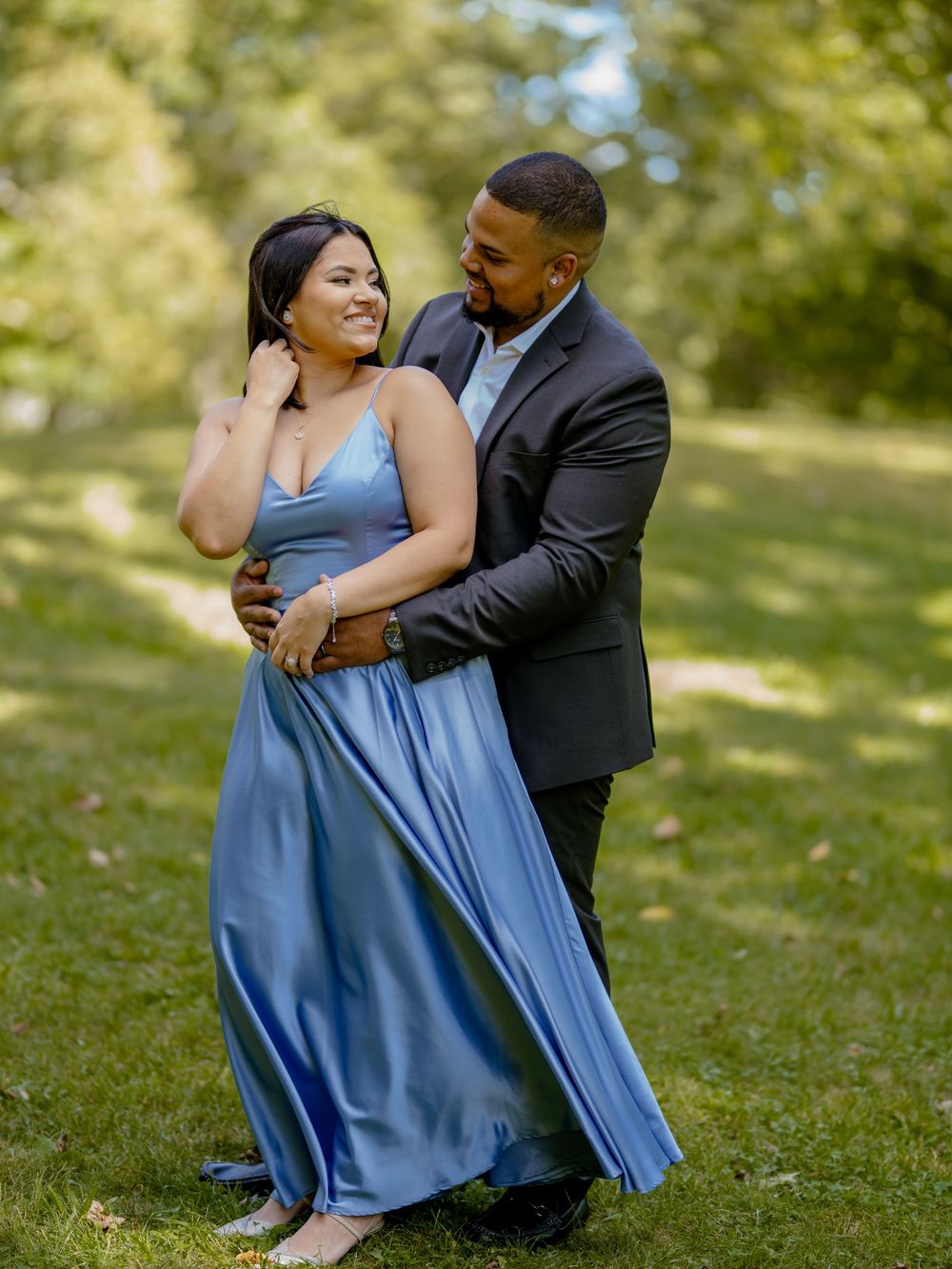 A romantic outdoor portrait of a couple embracing on a grassy lawn, dressed in elegant formal wear beautiful engagement shoot