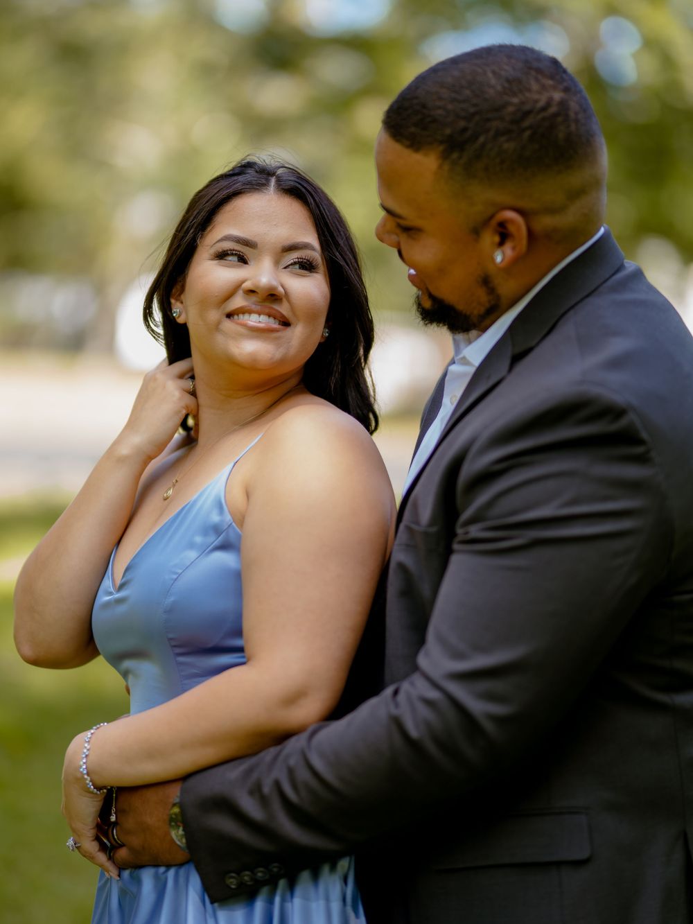 A couple shares intimate moments in an outdoor engagement photo session as they embrace and laugh together in natural light