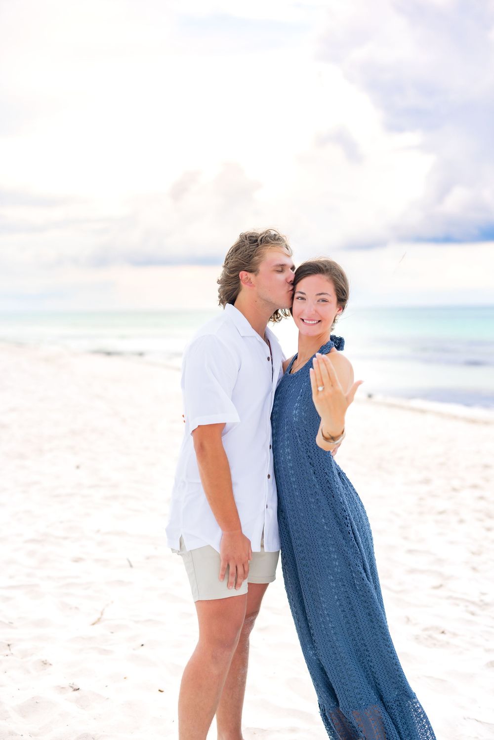 A couple shares a romantic moment together while walking on a pristine white sandy beach.