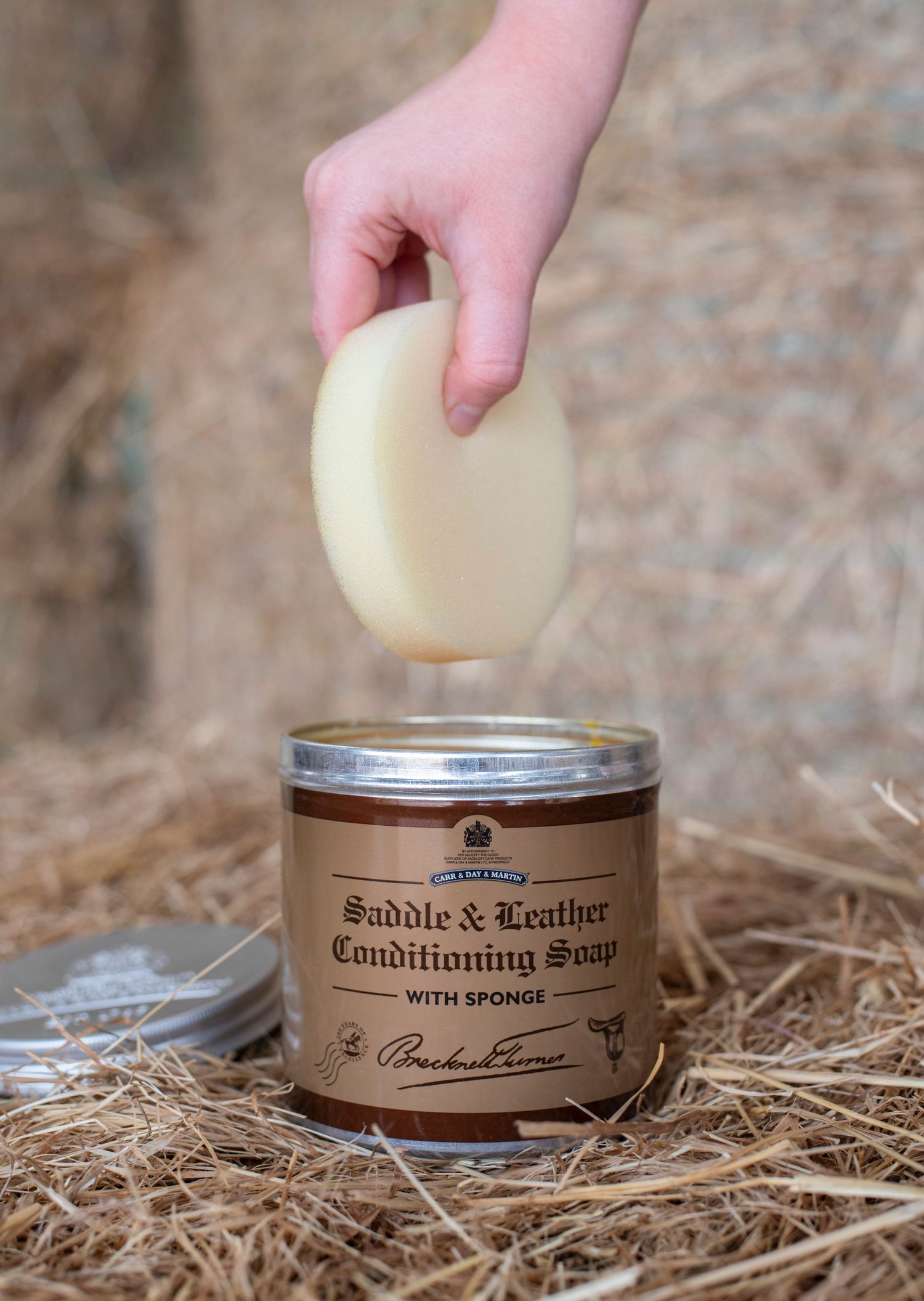 photo of a hand dipping a sponge into saddle soap to clean some tack