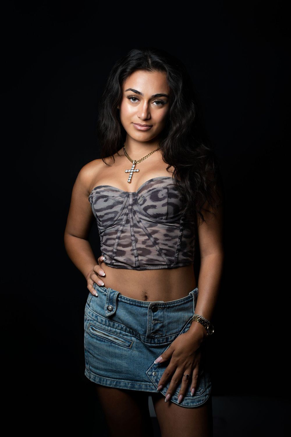 A model in a patterned crop top and denim shorts poses against a black background in a fashion photo sequence.