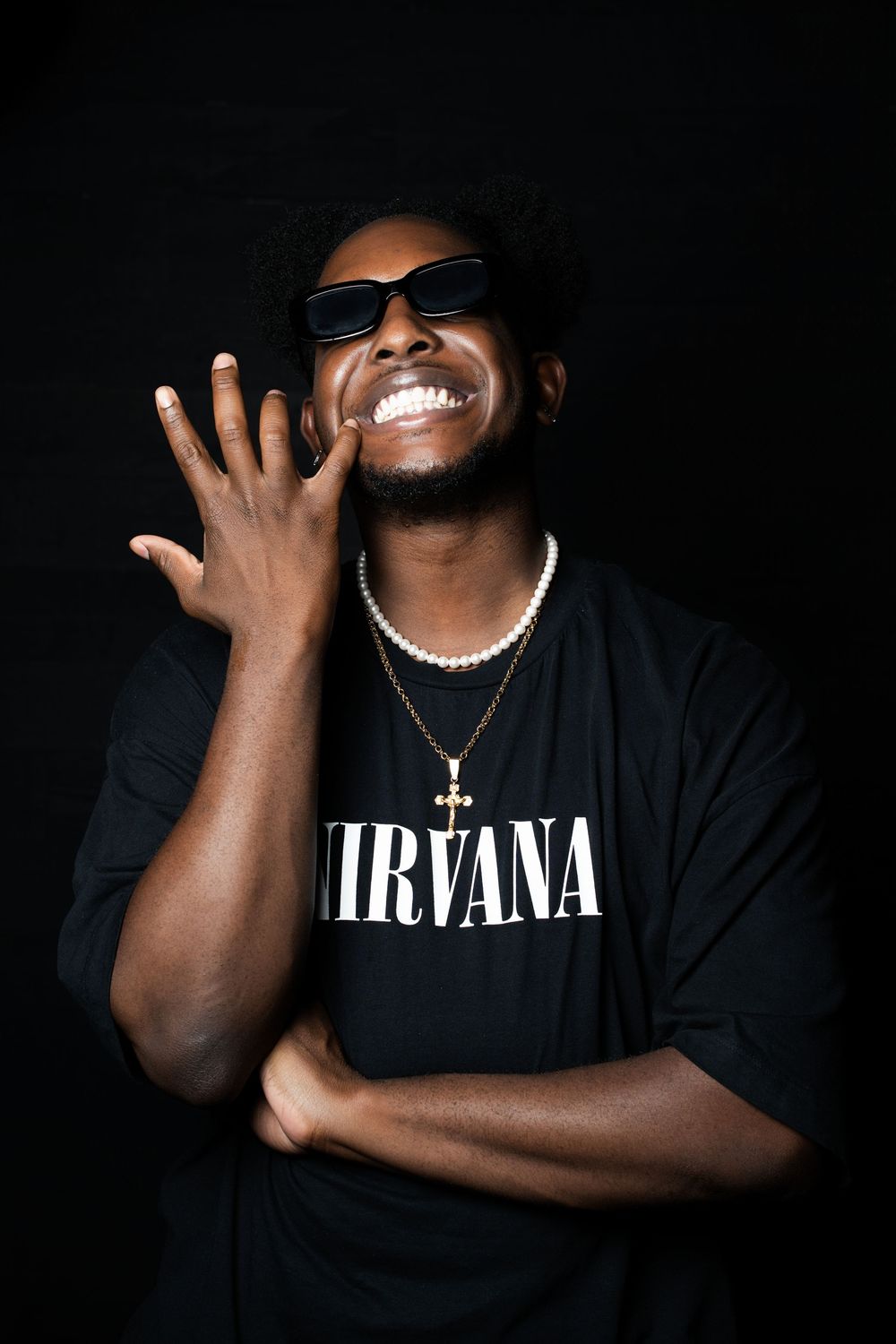 Five artistic portrait shots of a figure wearing dark clothing and jewelry against a black background showing different expressive poses.