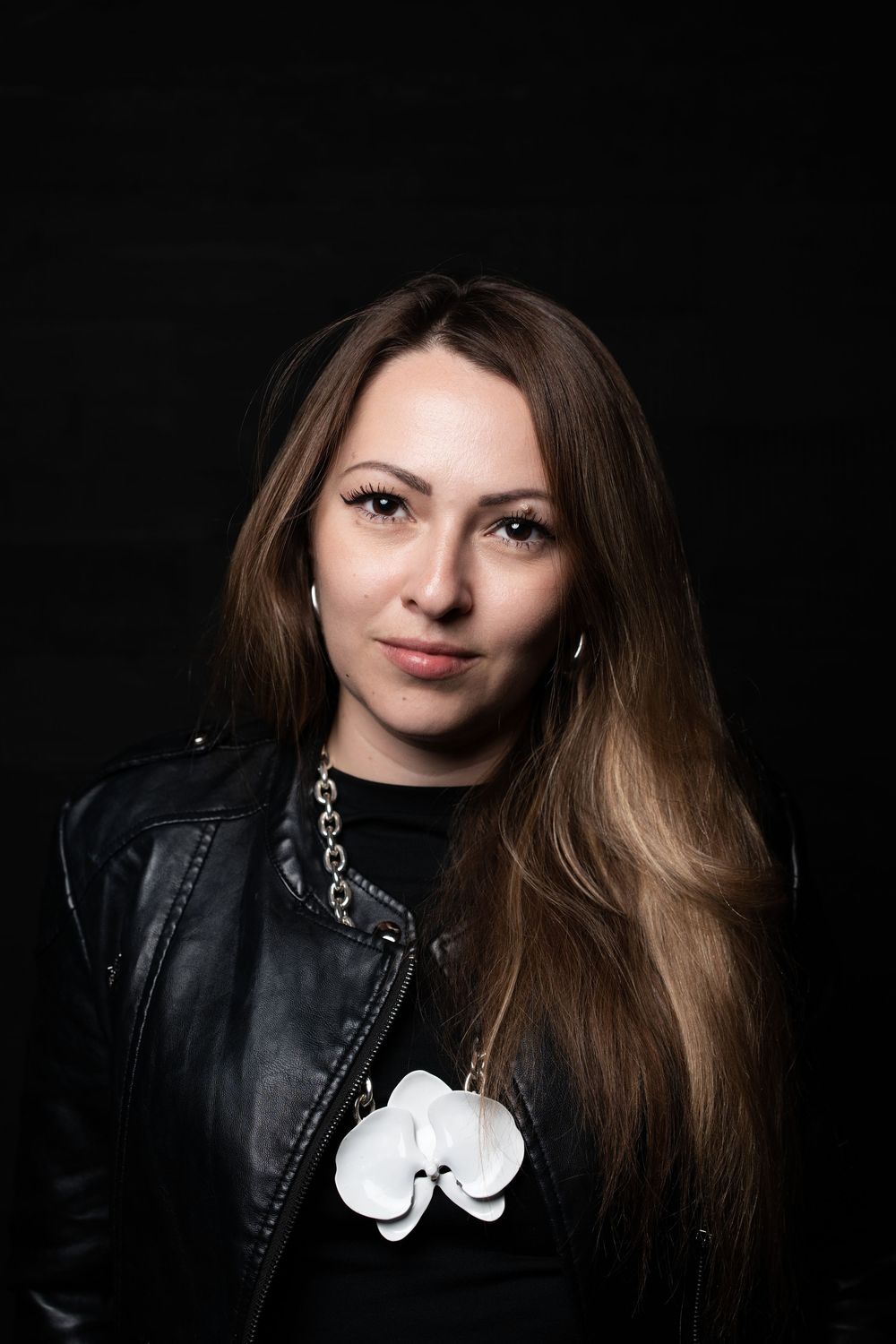 Stylish studio portrait series of a person with long brown hair wearing a black leather jacket and silver necklace.