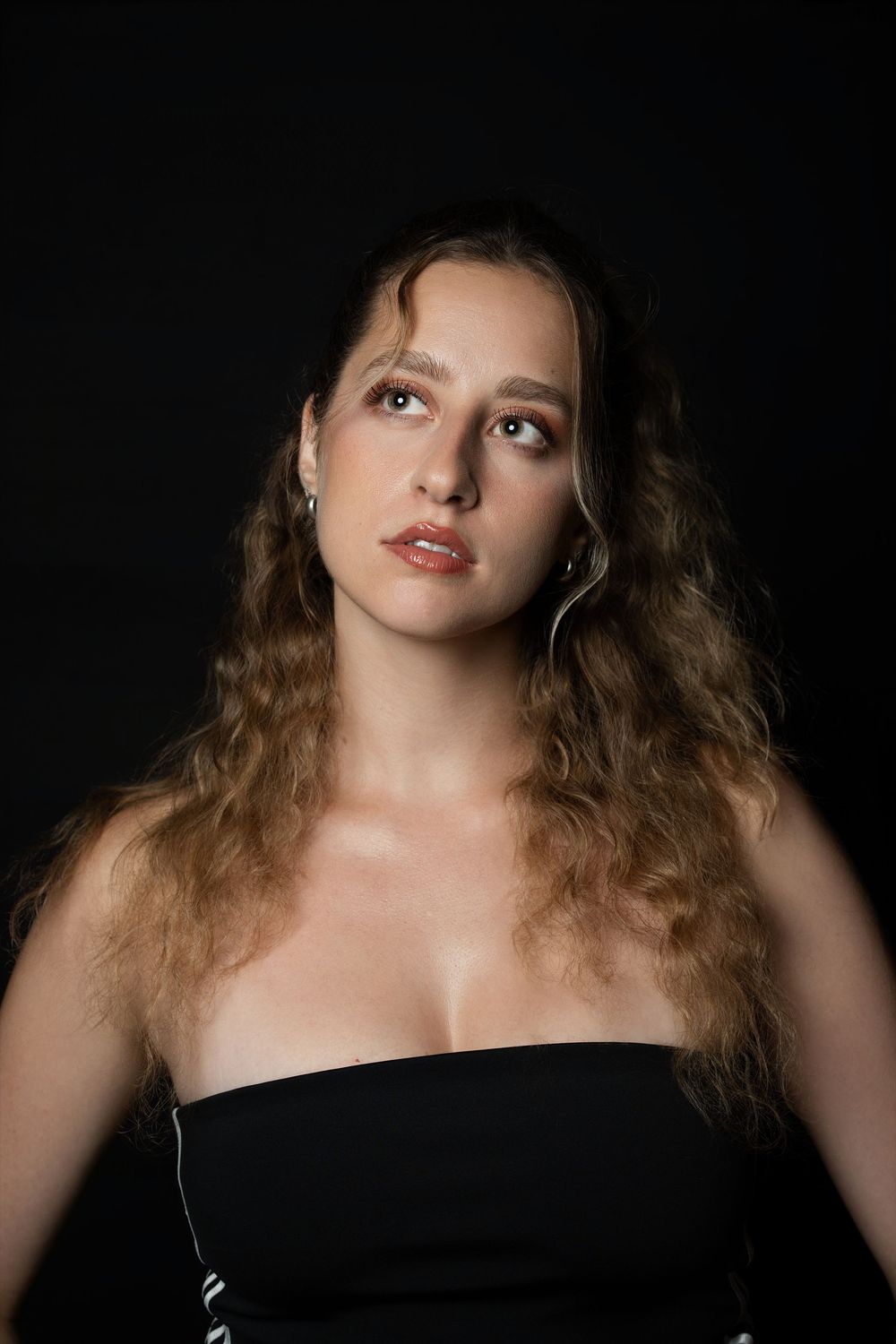 A dramatic portrait series against black background showing close-up views with red lipstick and curly hair.