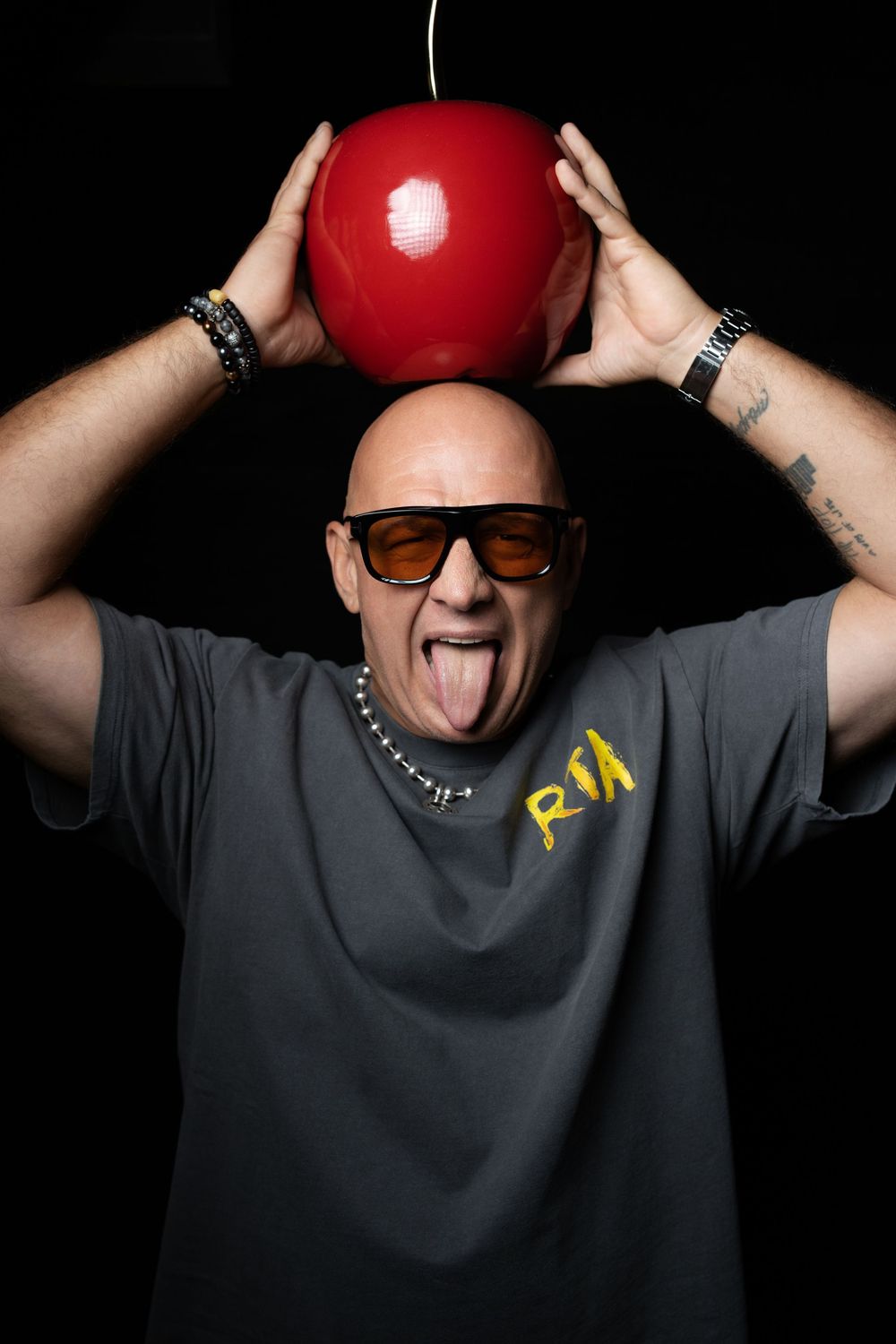 A series of five sequential photos showing someone playfully balancing a red ball on their head against a black background.