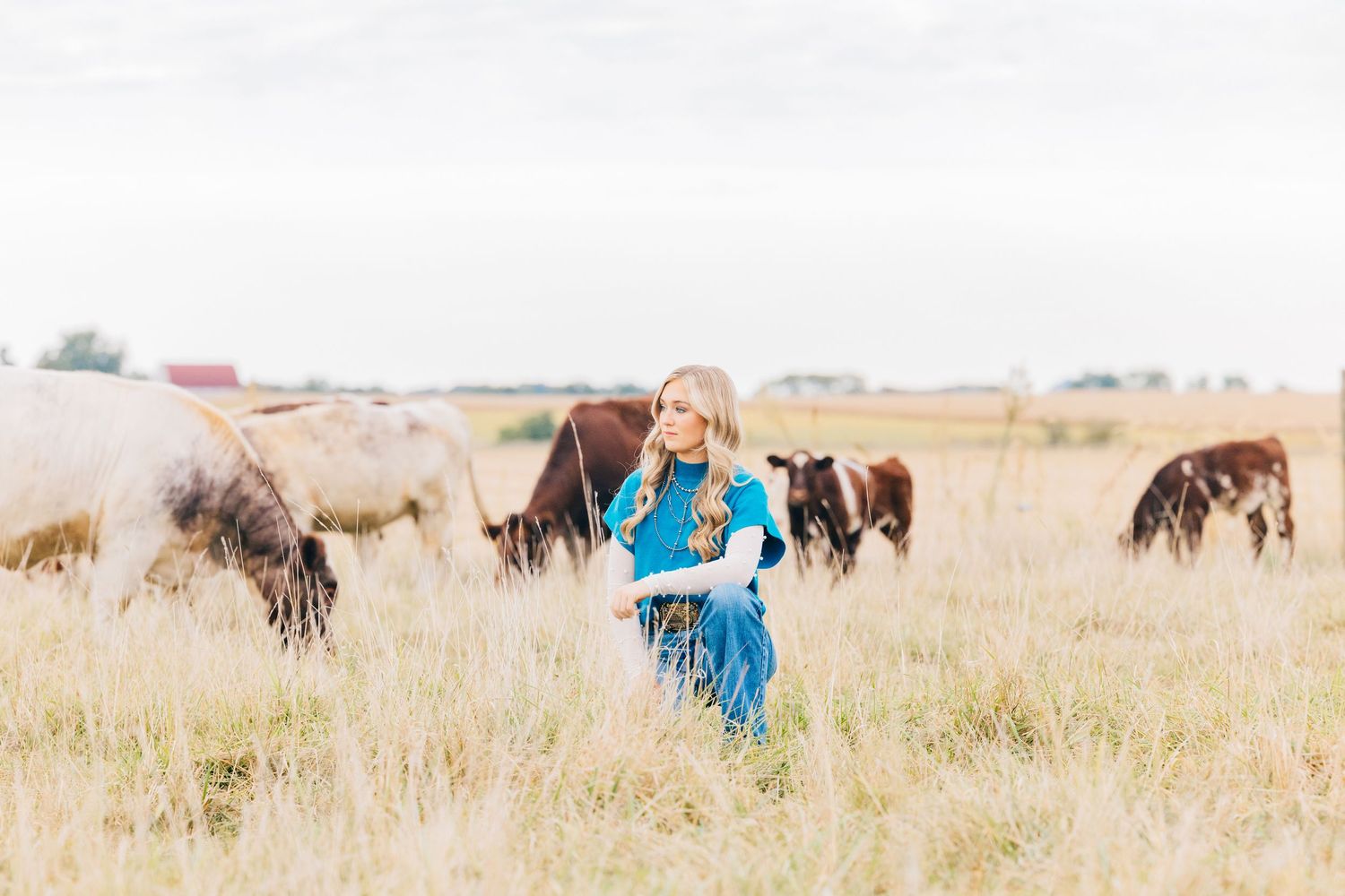 Senior in pasture with cattle grazing in the background