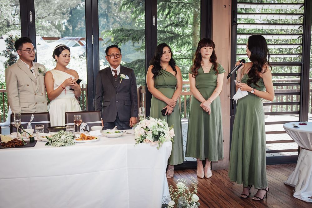 People in formal attire gather at an elegant wedding reception with a white tablecloth and floral decorations.