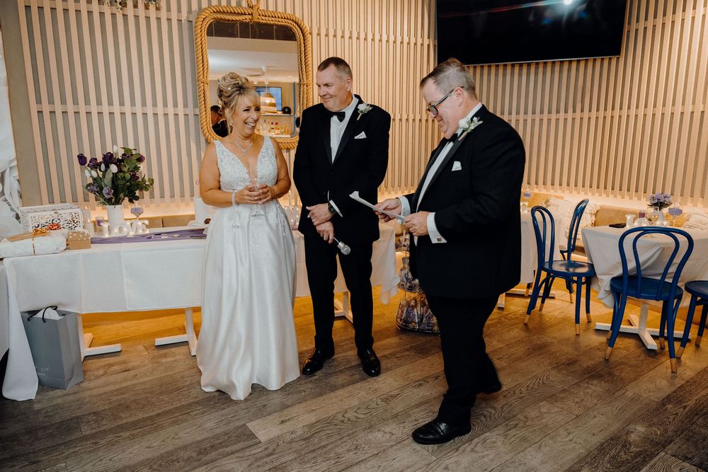 People gather in a modern event space with wooden slat wall panels during a formal celebration.