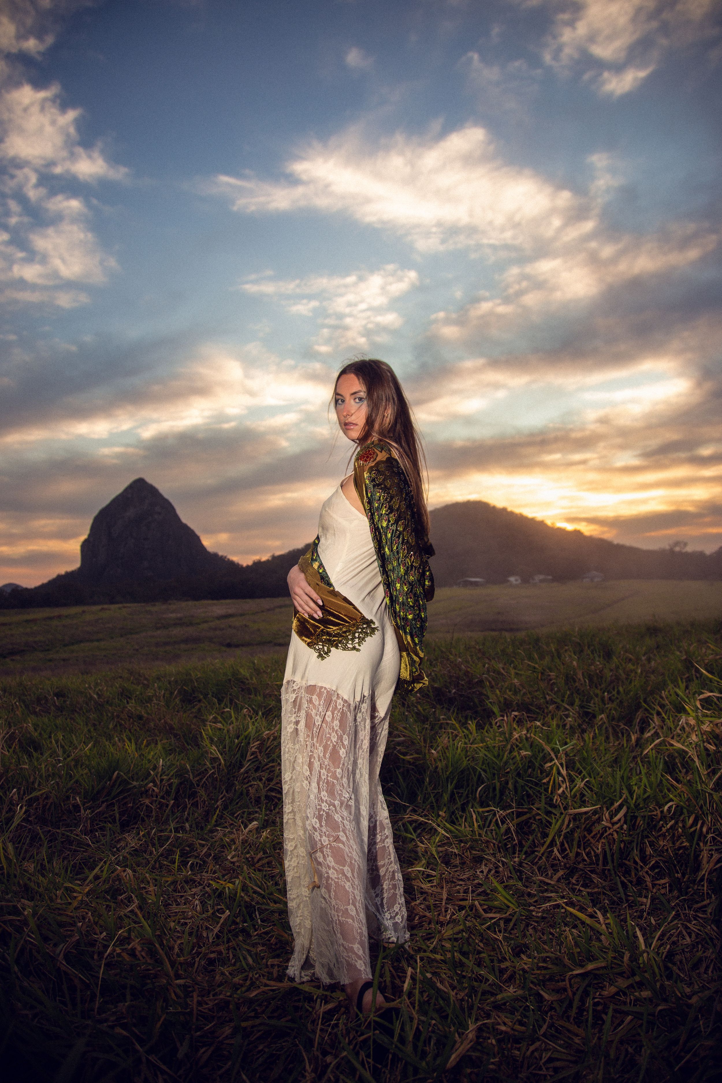 A romantic sunset photoshoot in a field with mountains in the background, captured in a triptych style composition.