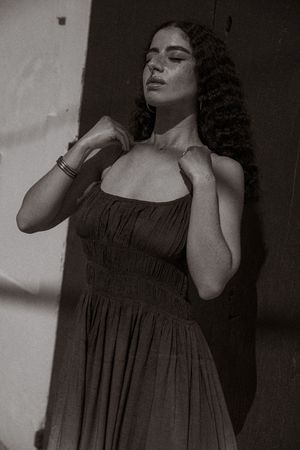 A dramatic black and white photo series showing a figure in a flowing dress posing expressively against a light background.