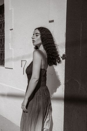 A black and white artistic portrait series showing a woman in a dress leaning against a wall in different poses.