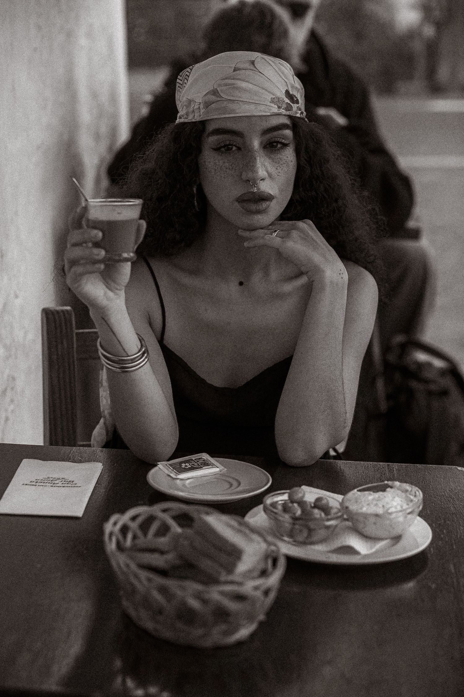 A black and white photo series showing someone dining alone at a cafe with coffee and food on the table.