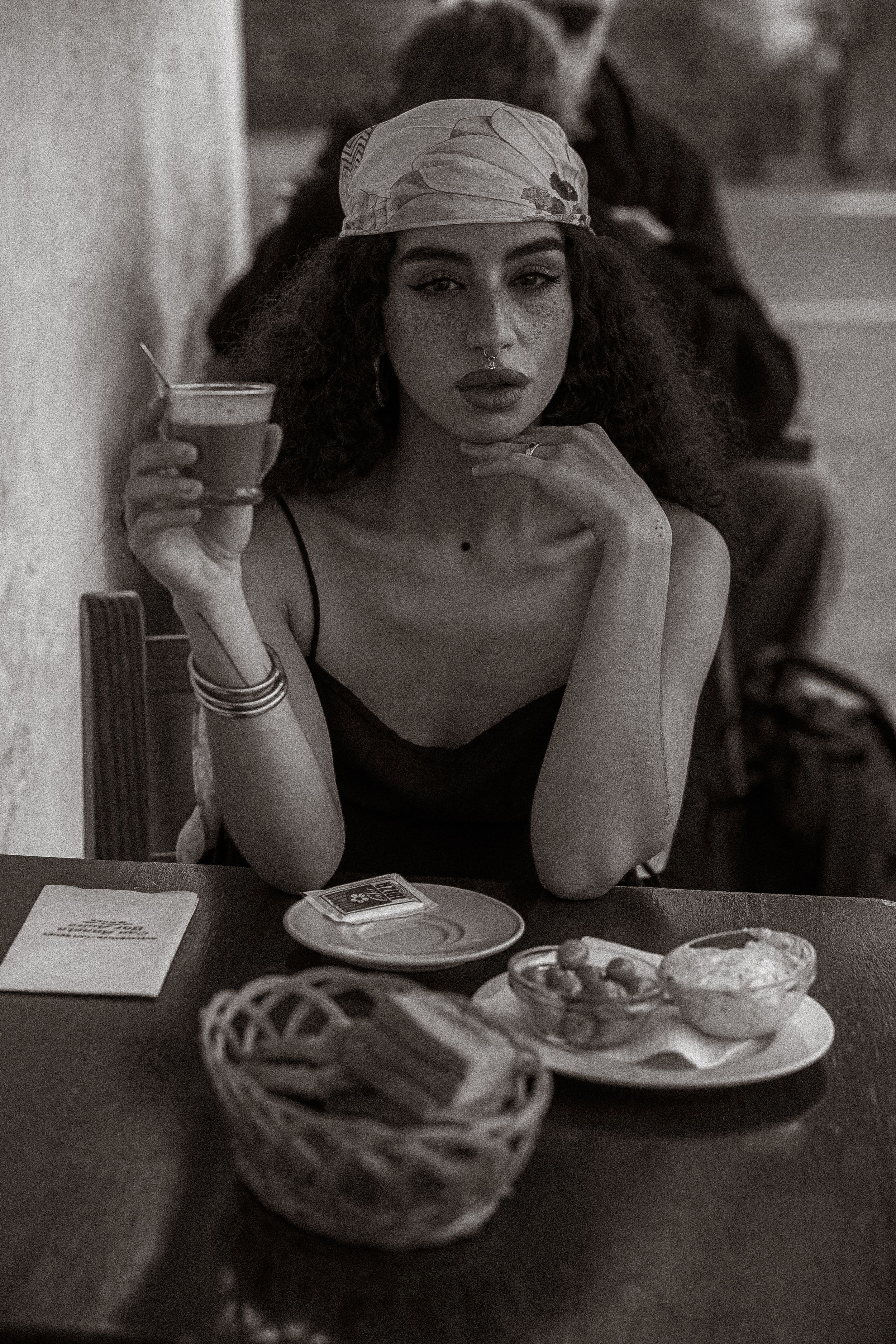 A black and white photo series showing someone dining alone at a cafe with coffee and food on the table.