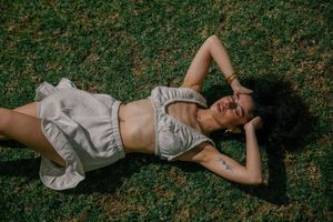 A person in light colored clothing lies on grass in a sequence of artistic outdoor portrait shots.