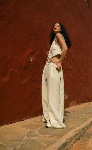 Fashion photo against terracotta wall features cream-colored matching set with wide-leg pants.