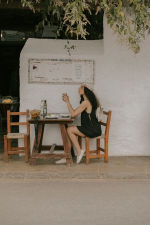 A series of photos showing someone sitting alone at a wooden desk against a white wall under tree branches.