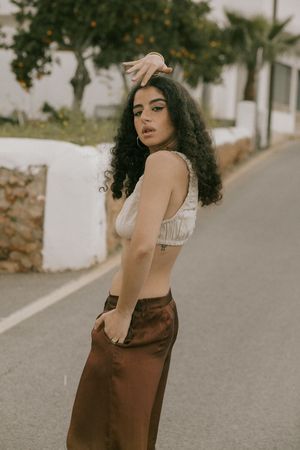 Fashion photo series showing poses in brown dress and white top on a sunny Mediterranean street.