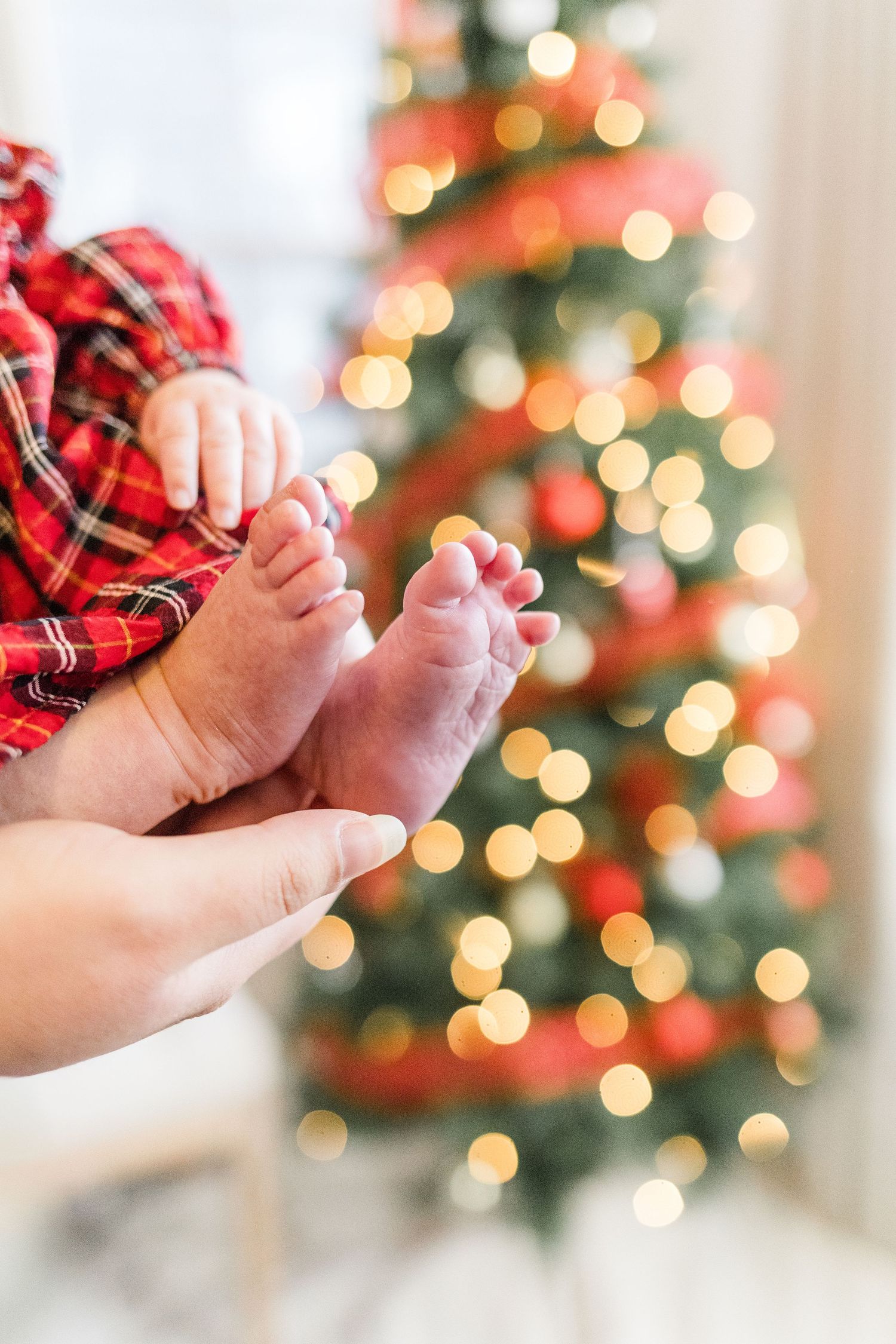 Baby feet in front of a blurry red + gold Christmas tree during a light + airy Hudson Valley, NY Christmas Mini Session.