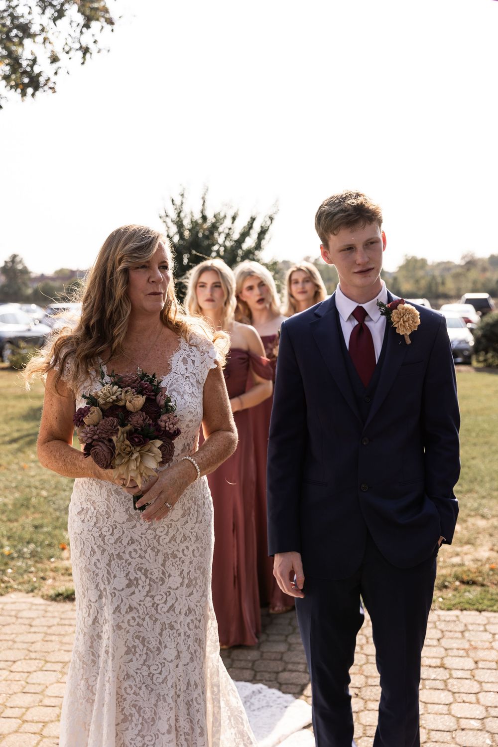 Wedding party gathered outdoors in burgundy and navy attire for a fall ceremony.