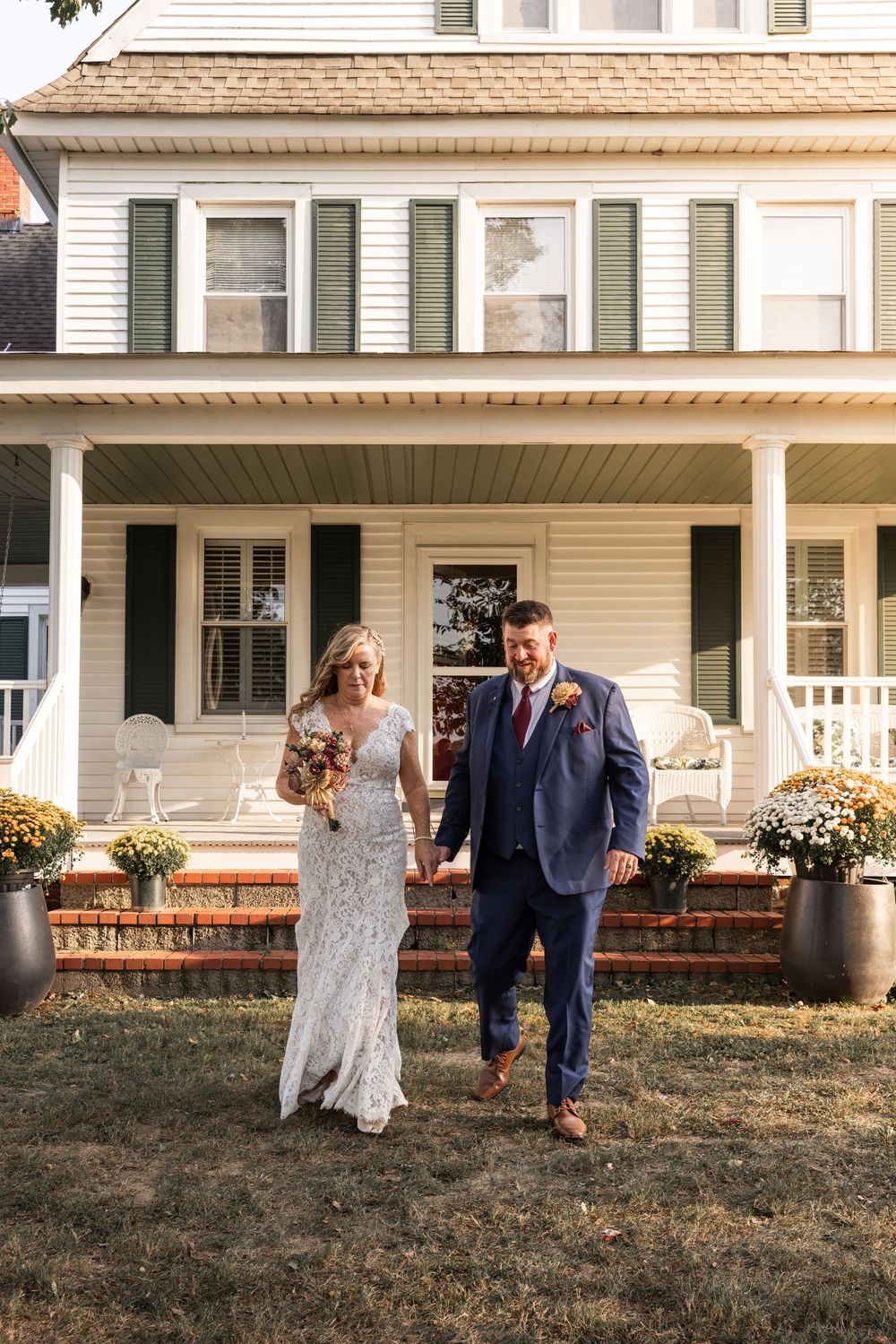Wedding celebration outside a classic white farmhouse with wraparound porch.
