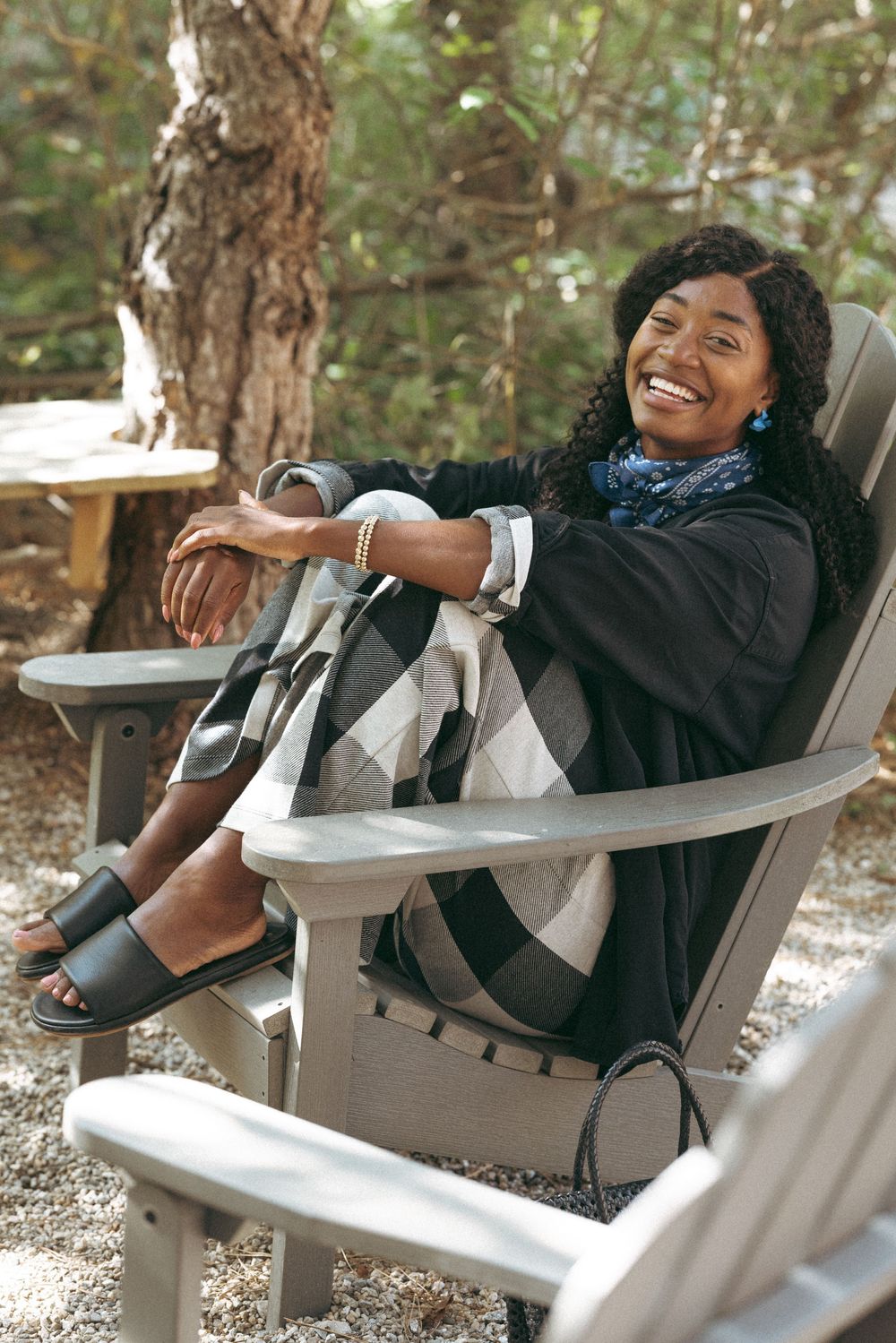 Person relaxing and laughing in outdoor Adirondack chair.