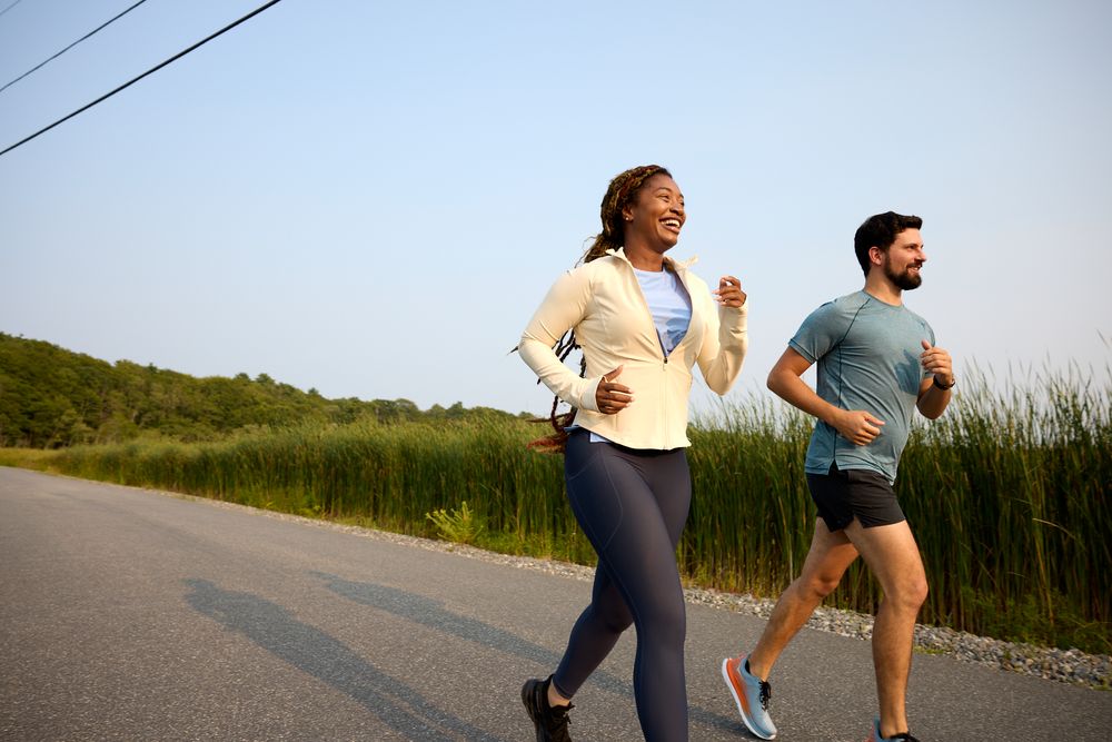 Group of people jogging together on rural road at sunset.