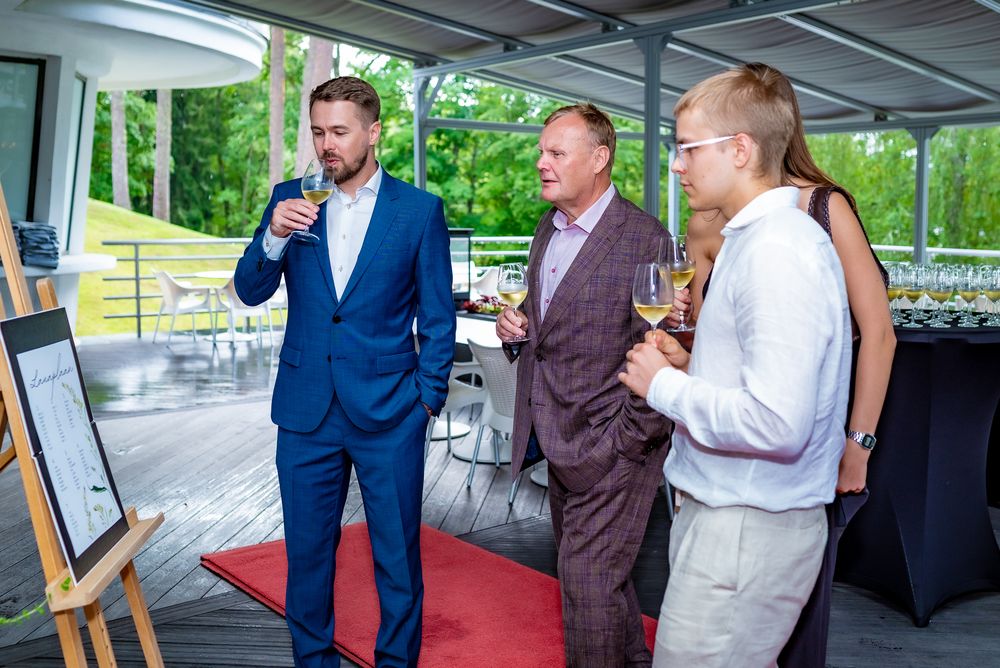 Business professionals engage in networking conversations at an outdoor covered event space.
