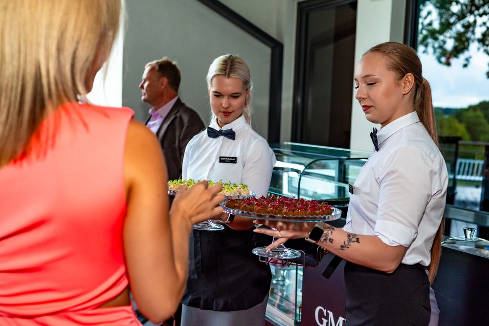 Restaurant servers in white shirts gather at a counter to review orders and paperwork during service.