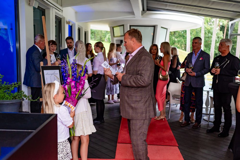 Wedding guests gather under a covered outdoor venue decorated with blue accents during a celebration.