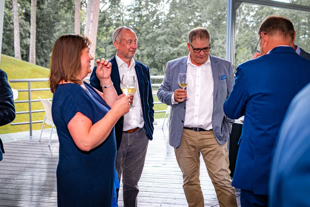 People in formal attire socialize and mingle at an outdoor networking event.