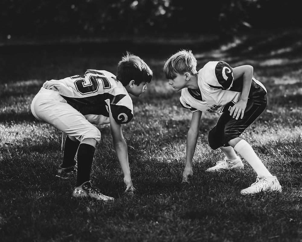 Baseball players perform warmup stretches on grass field in vintage black and white photograph.