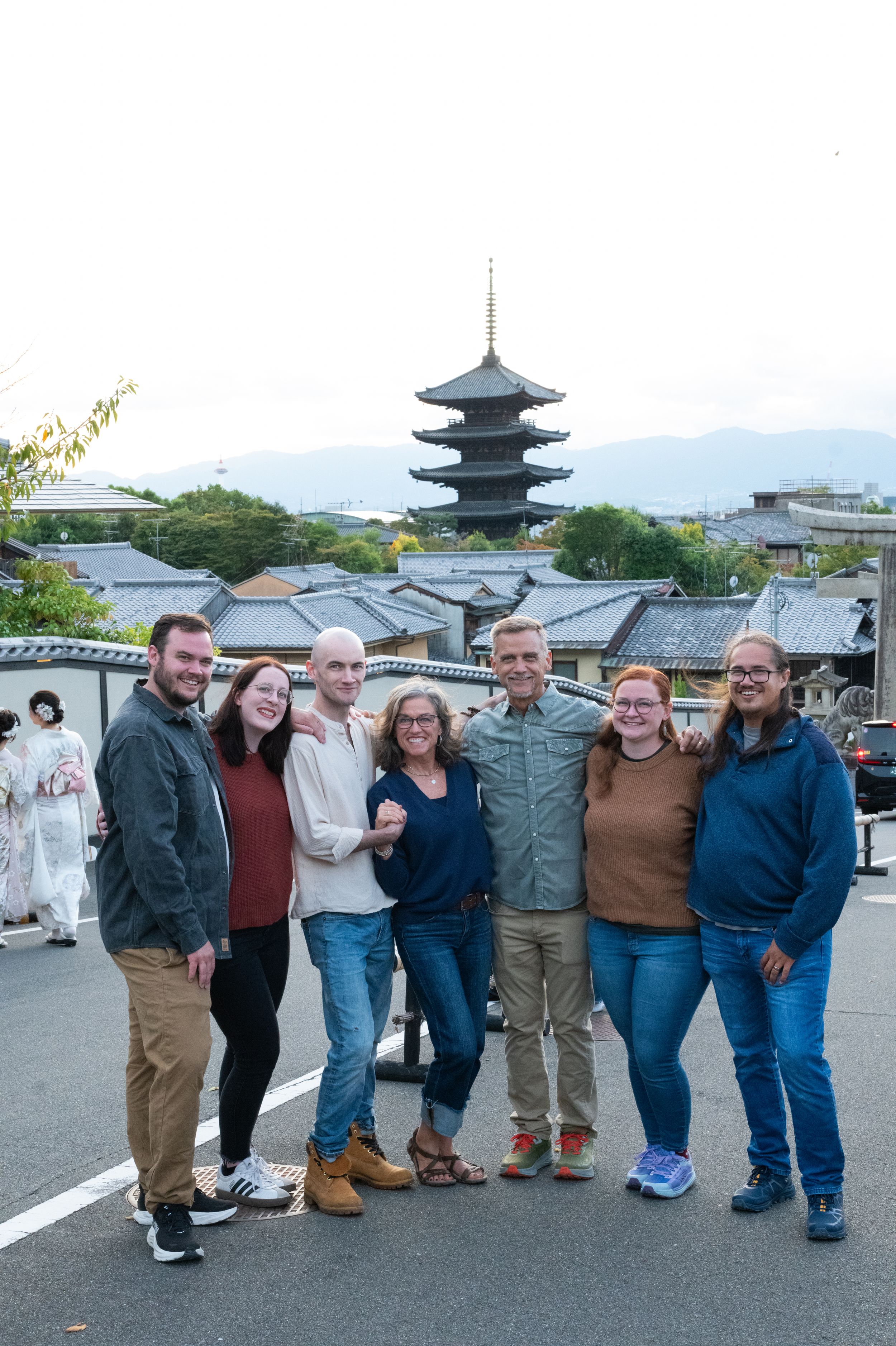 Family of seven smiling together with a Japanese five-story pagoda visible in the background.