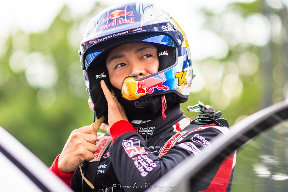 Race car driver in a Red Bull helmet looks focused while sitting in the cockpit during a motorsport event.