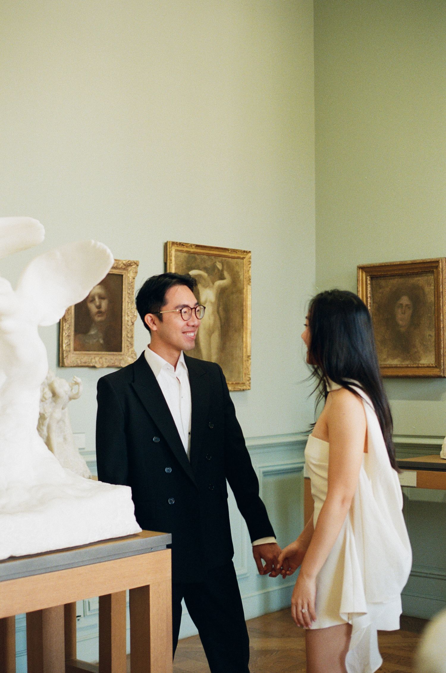 Romantic wedding couple embraces in an elegant room with ornate mint green walls and classic architectural details.