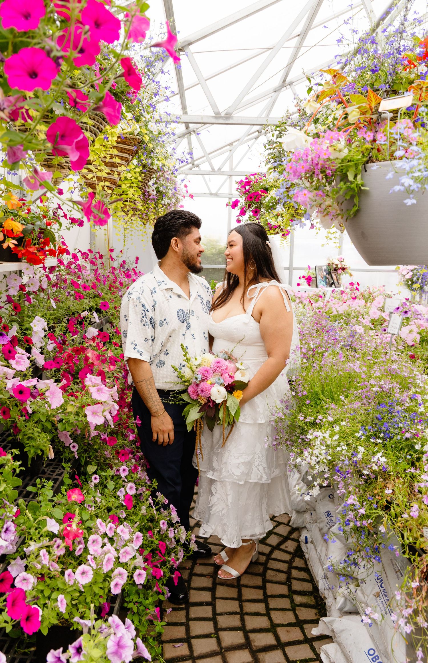 Wedding guests laugh together at an outdoor reception with colorful floral centerpieces and string lights.