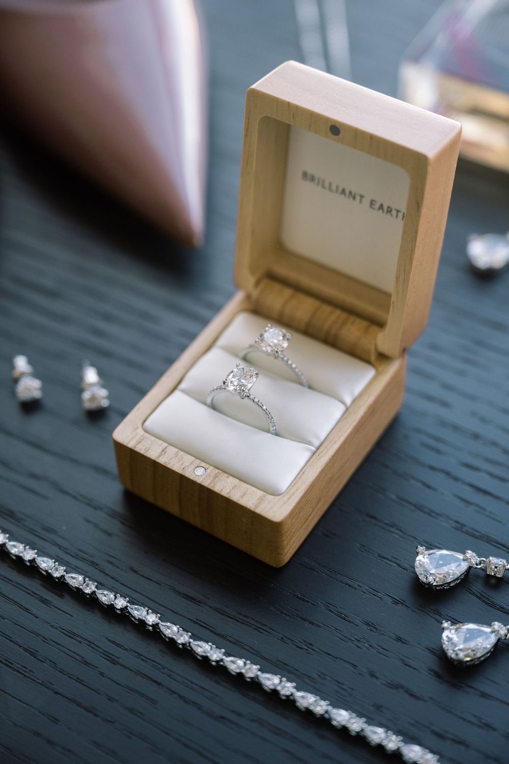 Diamond engagement ring displayed in wooden box with matching jewelry pieces.