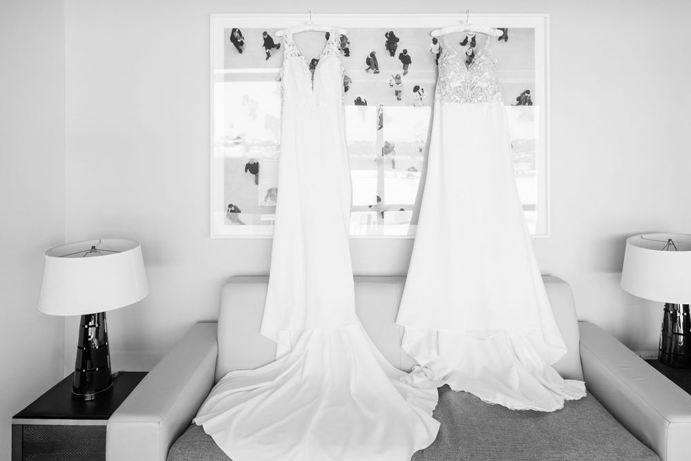 White wedding dresses displayed on hangers in bright room with natural lighting.