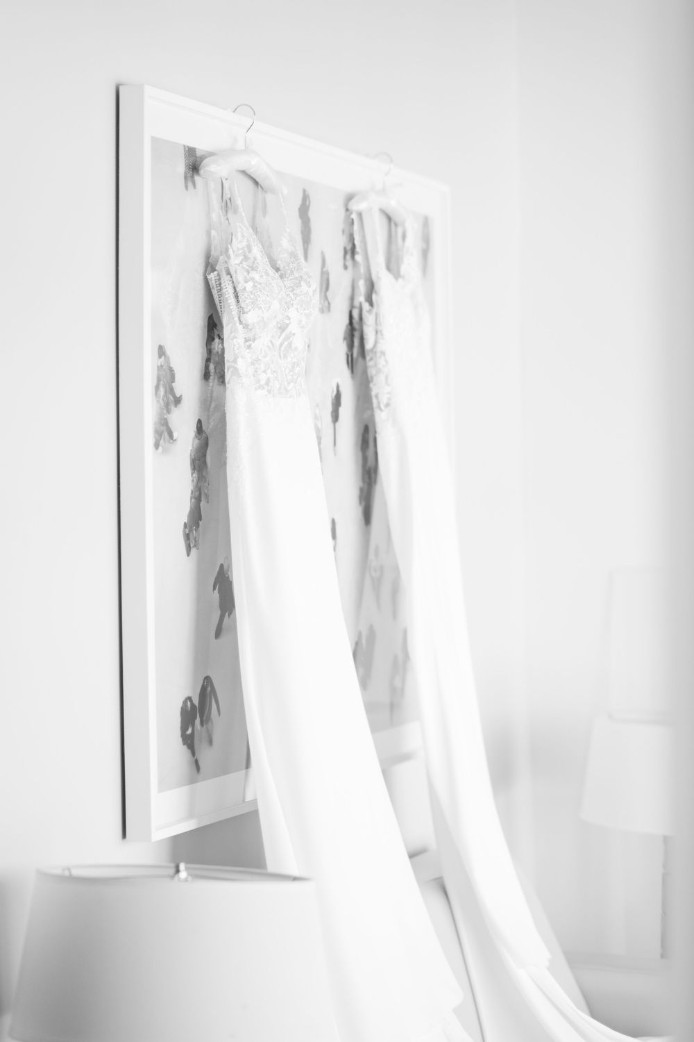 Ethereal white wedding dresses hanging in minimalist room with soft lighting.