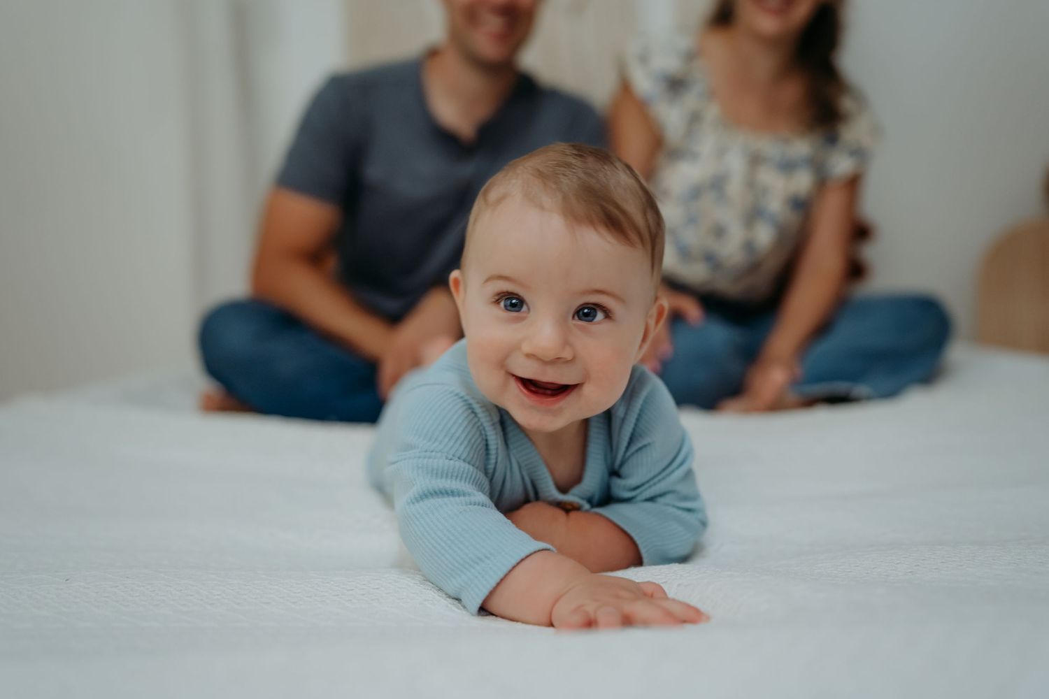 A series of candid photos showing a baby's progression from lying on their stomach to sitting up on a white bed.