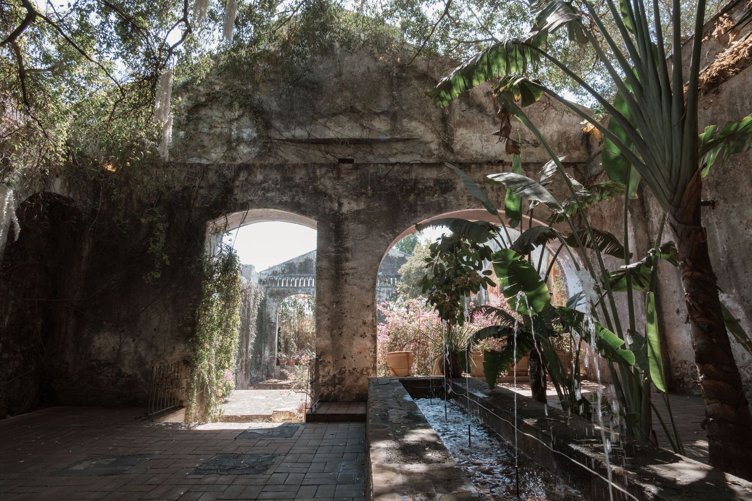 Stone archways and tropical plants create a romantic garden pathway.