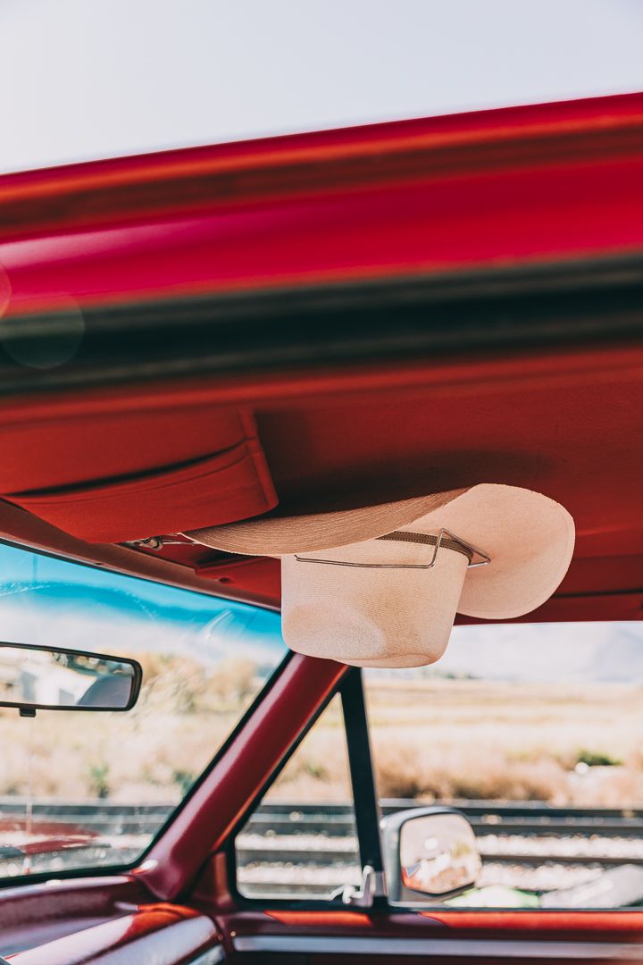 Interior view of a vintage car showing the red headliner and windshield against a bright sky background.