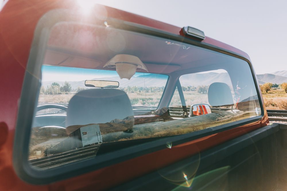 A panoramic view through a car windshield shows a scenic mountain landscape stretching across multiple frames.