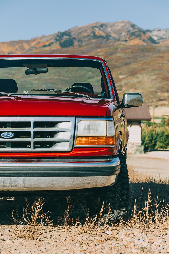 Front view of a red Ford F-150 pickup truck parked against a mountainous desert backdrop.