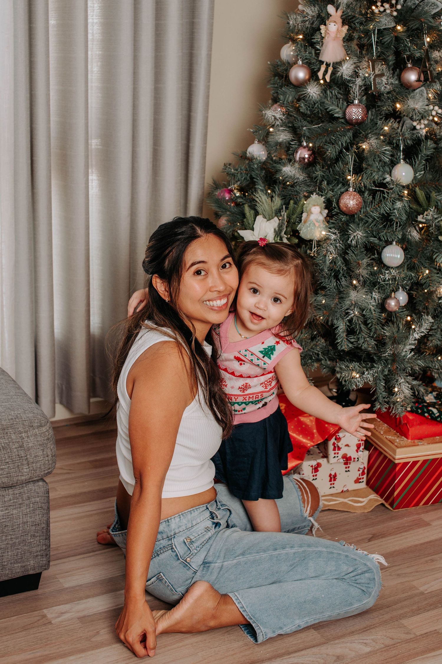 Family enjoying Christmas morning together by decorated tree with presents and white ornaments.