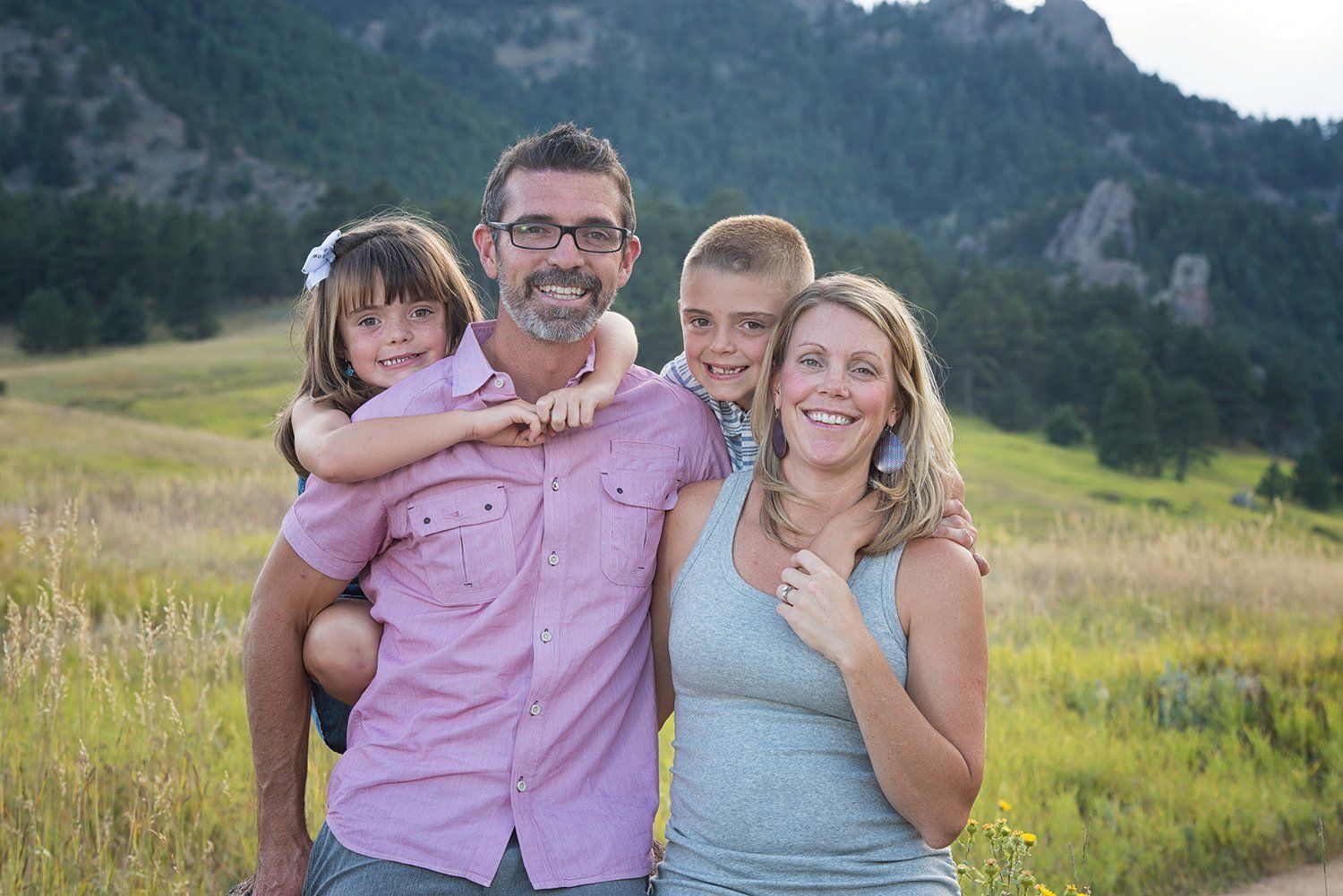 A Erie Colorado family portrait session in a scenic mountain meadow with wildflowers and natural lighting at sunset.