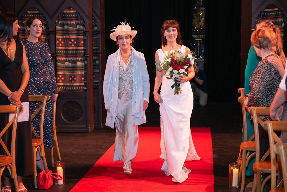 Wedding guests seated in a historic church venue with ornate architecture and a red carpet aisle.