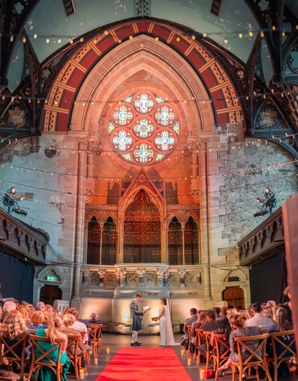 Panoramic view of a church wedding setup with gothic windows and dramatic lighting.