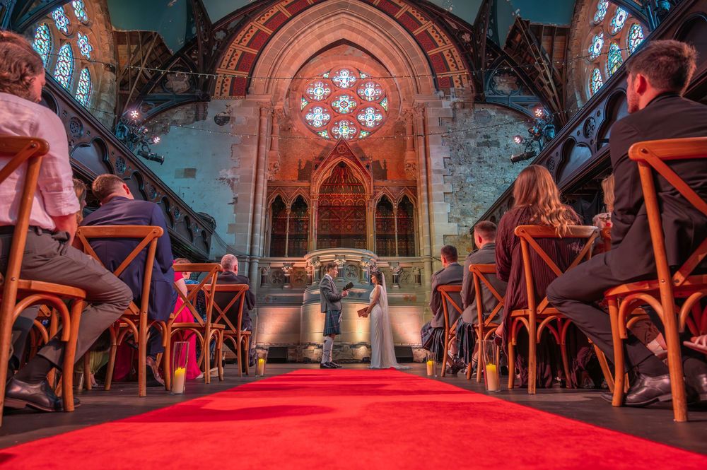 Dramatic wide-angle view of a red-carpeted church aisle with cross-back chairs.